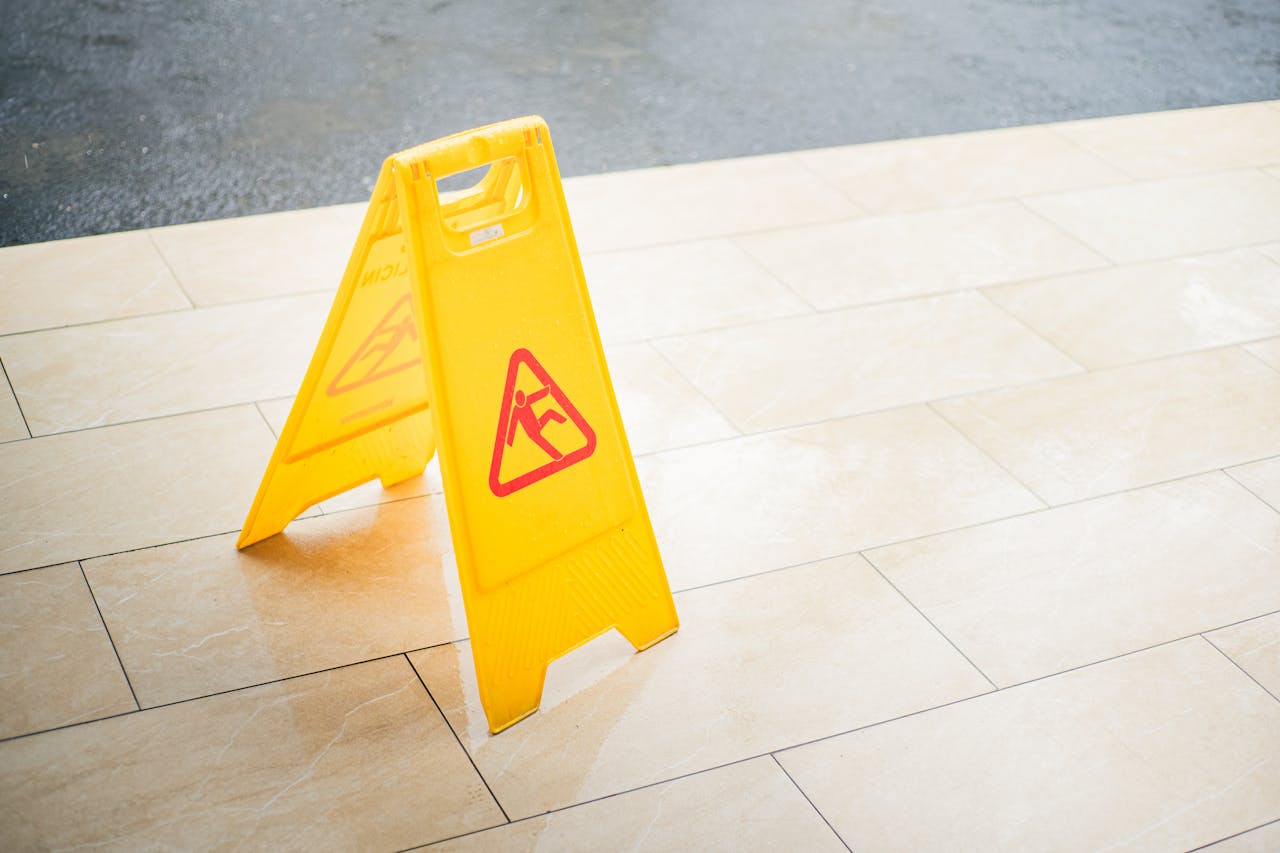 services-03 A bright yellow caution sign placed on a tile floor indicating a wet area for safety.