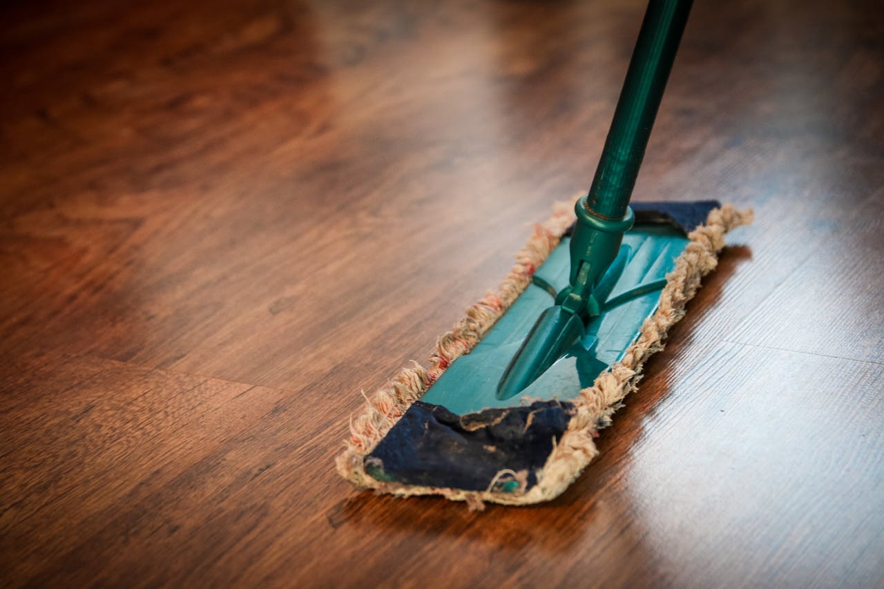 about-01 A detailed view of a mop cleaning a wooden floor, showing texture and pattern.